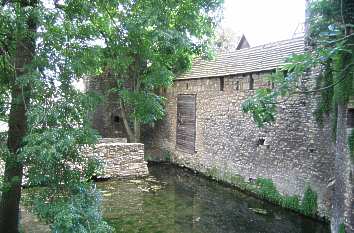 Wassergraben und Burgmauer mit hochgezogener Zugbrücke