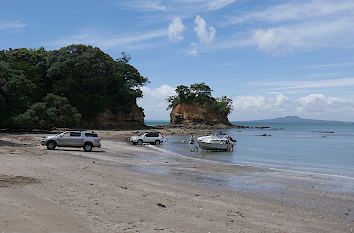 Boote und Autos am Waiacke Beach in Auckland